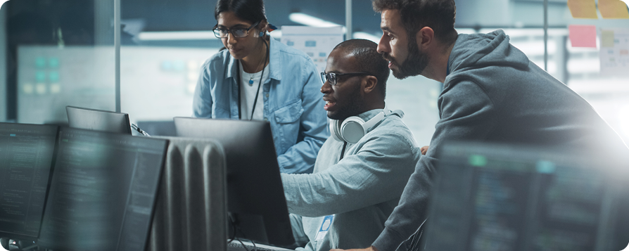 Three males standing in front of a computer monitor